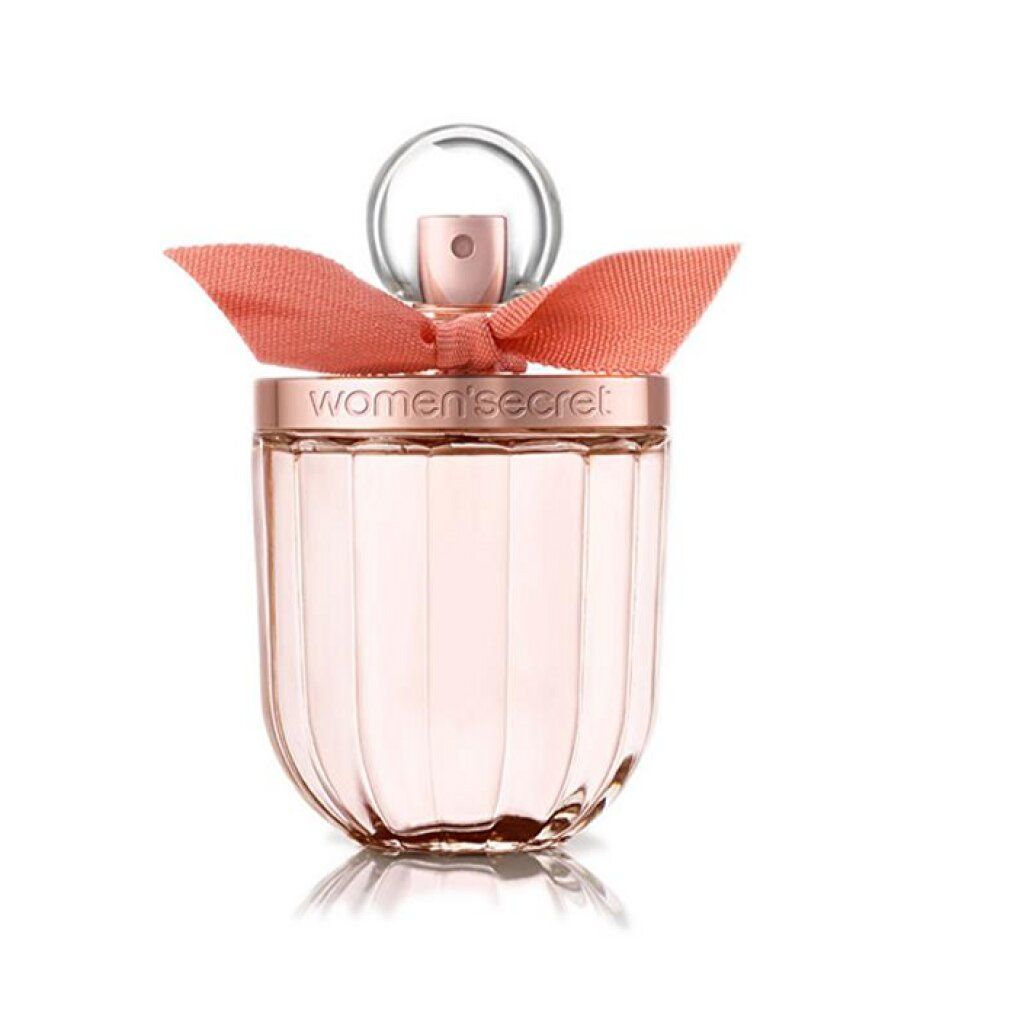 Flacone in vetro con fiocco rosa. Il flacone ha un tappo rotondo e un corpo scanalato. "women secret" è scritto sul tappo.