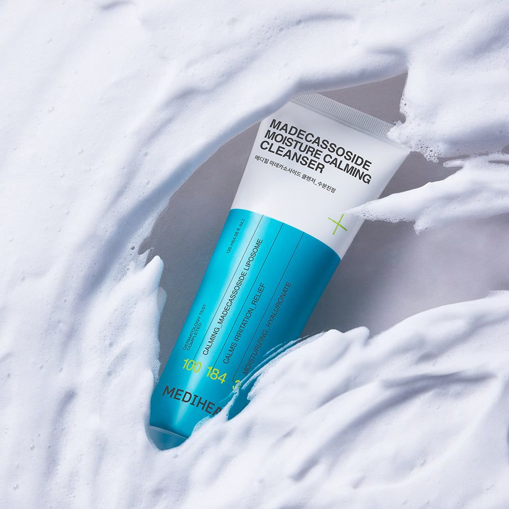 Tubo bianco e blu nella schiuma. Scritta: Madecassoside Moisture Calming Cleanser. Marchio: MEDIHEAL. Testo in inglese e coreano.