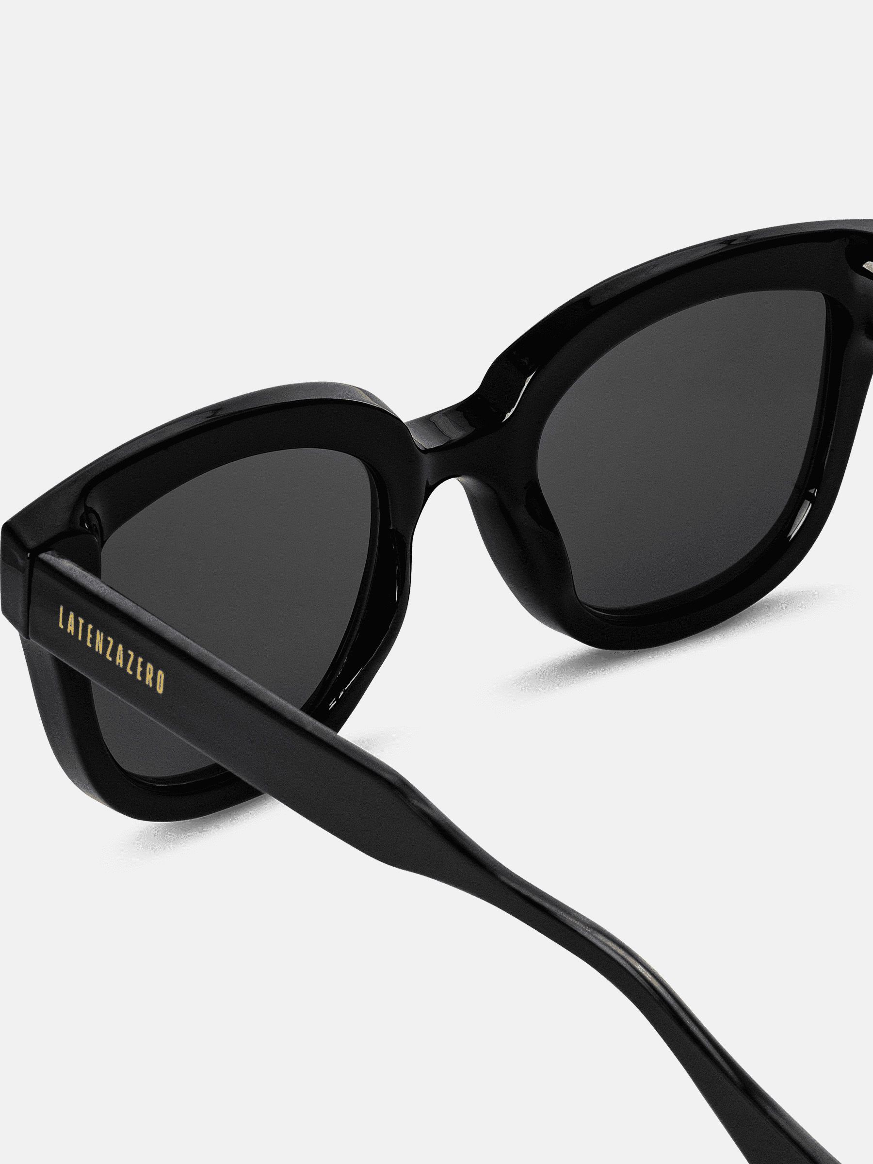 Primo piano di occhiali da sole neri. Logo Latenzazero sull'asta. Lenti scure.