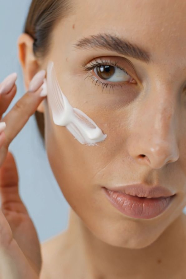 Donna che applica la crema sul viso. Crema visibile sulla pelle.
