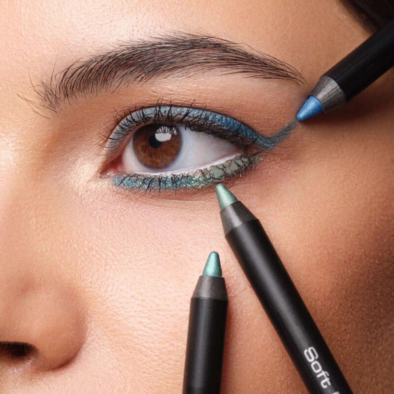 Occhio con eyeliner blu e verde, tenuto da tre matite.