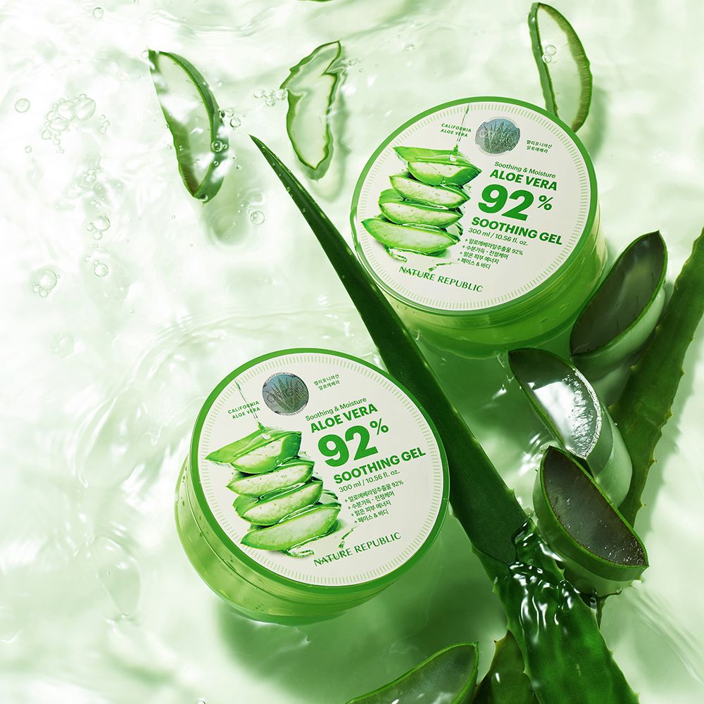 Due contenitori di gel verde con coperchi. Accanto, foglie di aloe vera. Sul coperchio, "Aloe Vera 92% Soothing Gel".