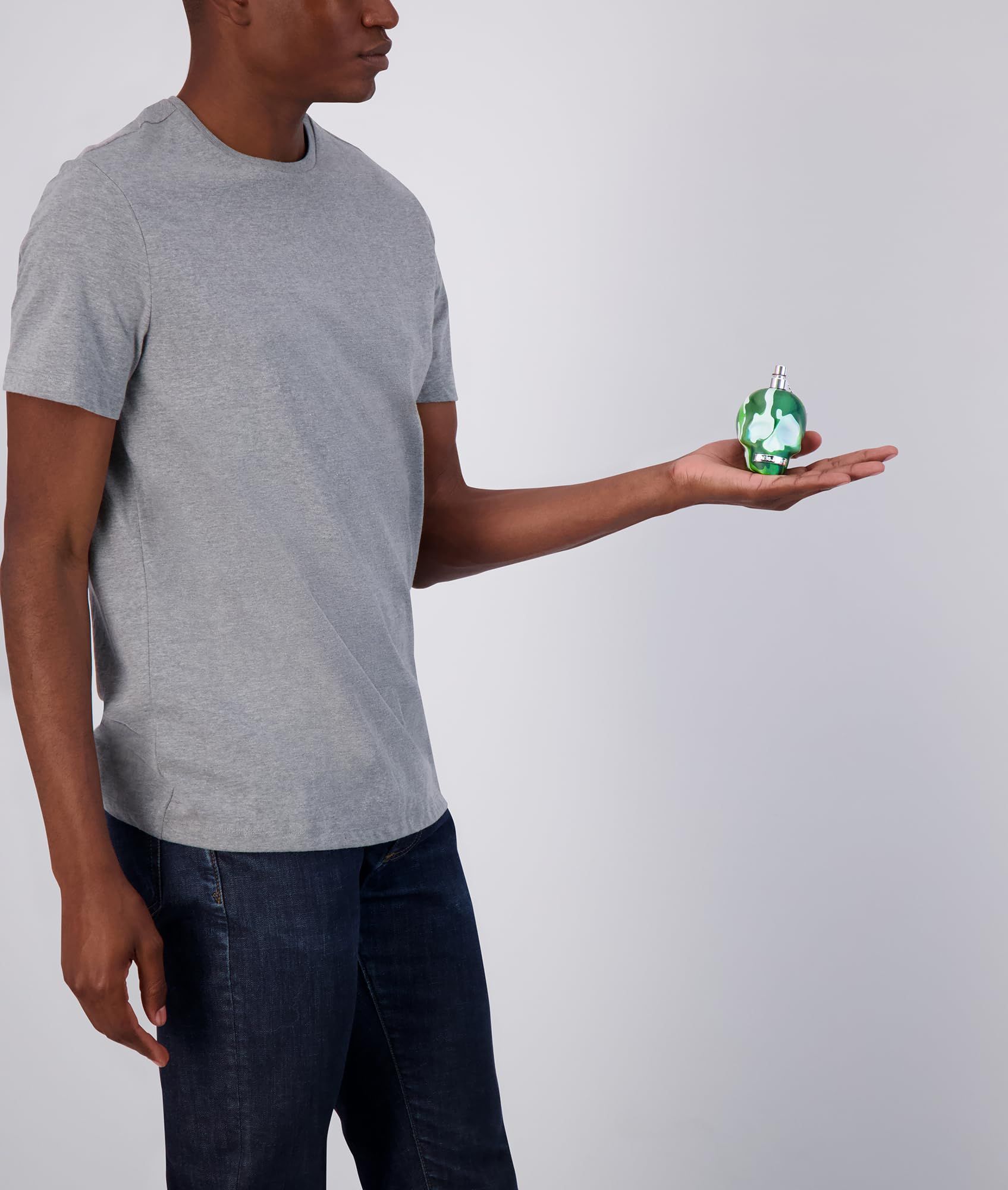 Persona che tiene in mano un flacone a teschio mimetico. Vaporizzatore argentato.