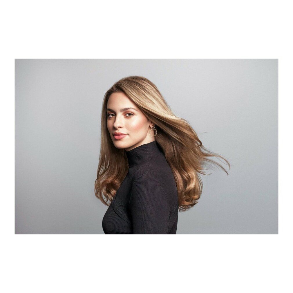 Ritratto di donna con lunghi capelli biondi mossi dal vento. Indossa un dolcevita nero.