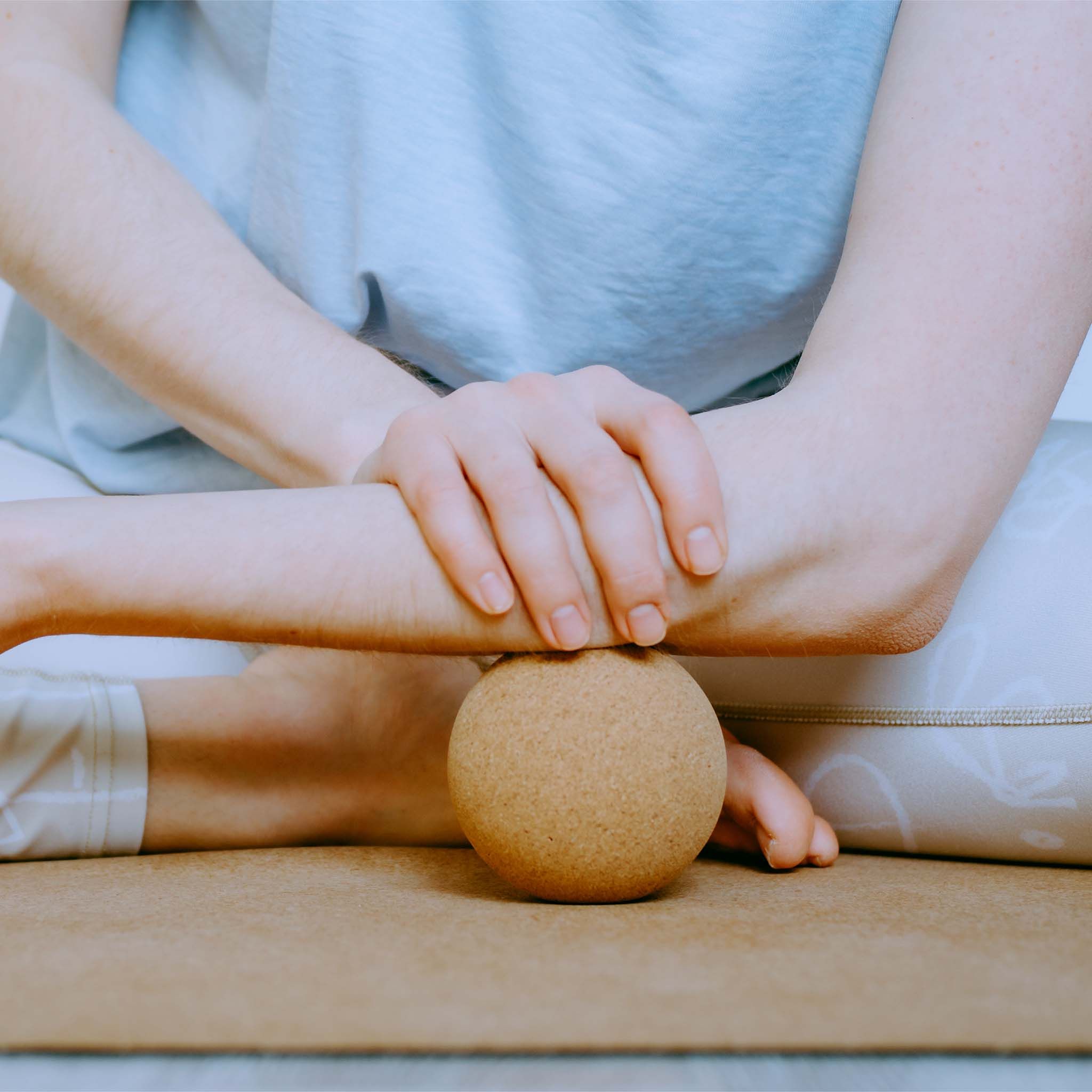 Persona usa una sfera in sughero sotto il braccio. Su un tappetino. Sughero naturale.