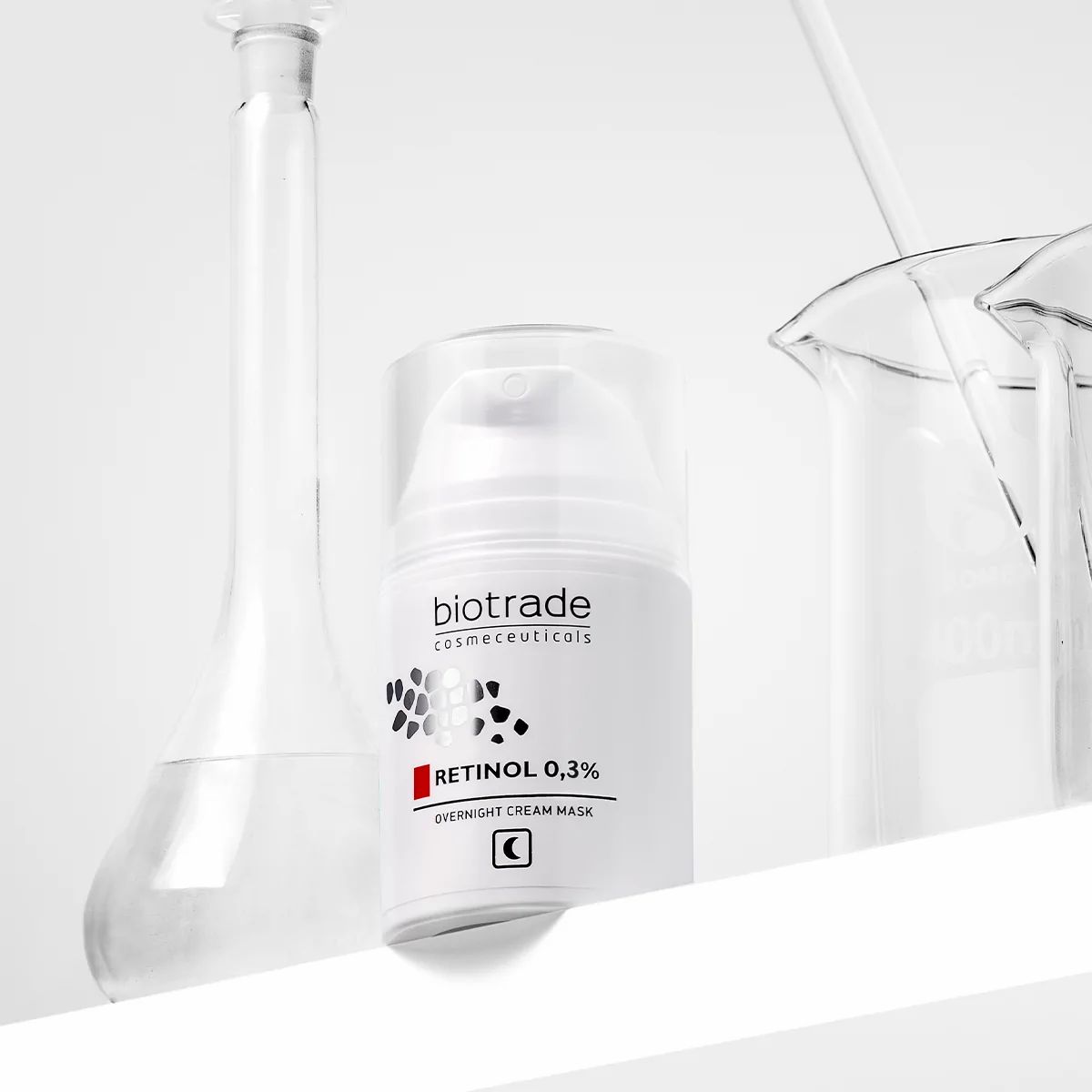 Flacone bianco Biotrade, Retinolo 0,3% e maschera notte. Accanto a vetreria da laboratorio.