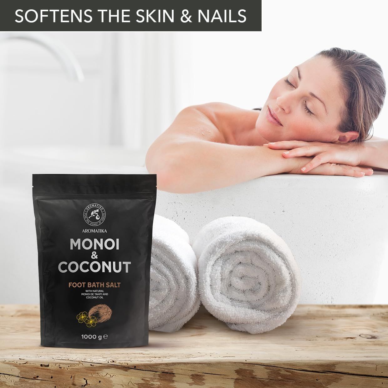 Confezione del prodotto accanto a una donna nella vasca da bagno. Gli asciugamani sono accanto. Testo: Monoi & Coconut Foot Bath Salt.