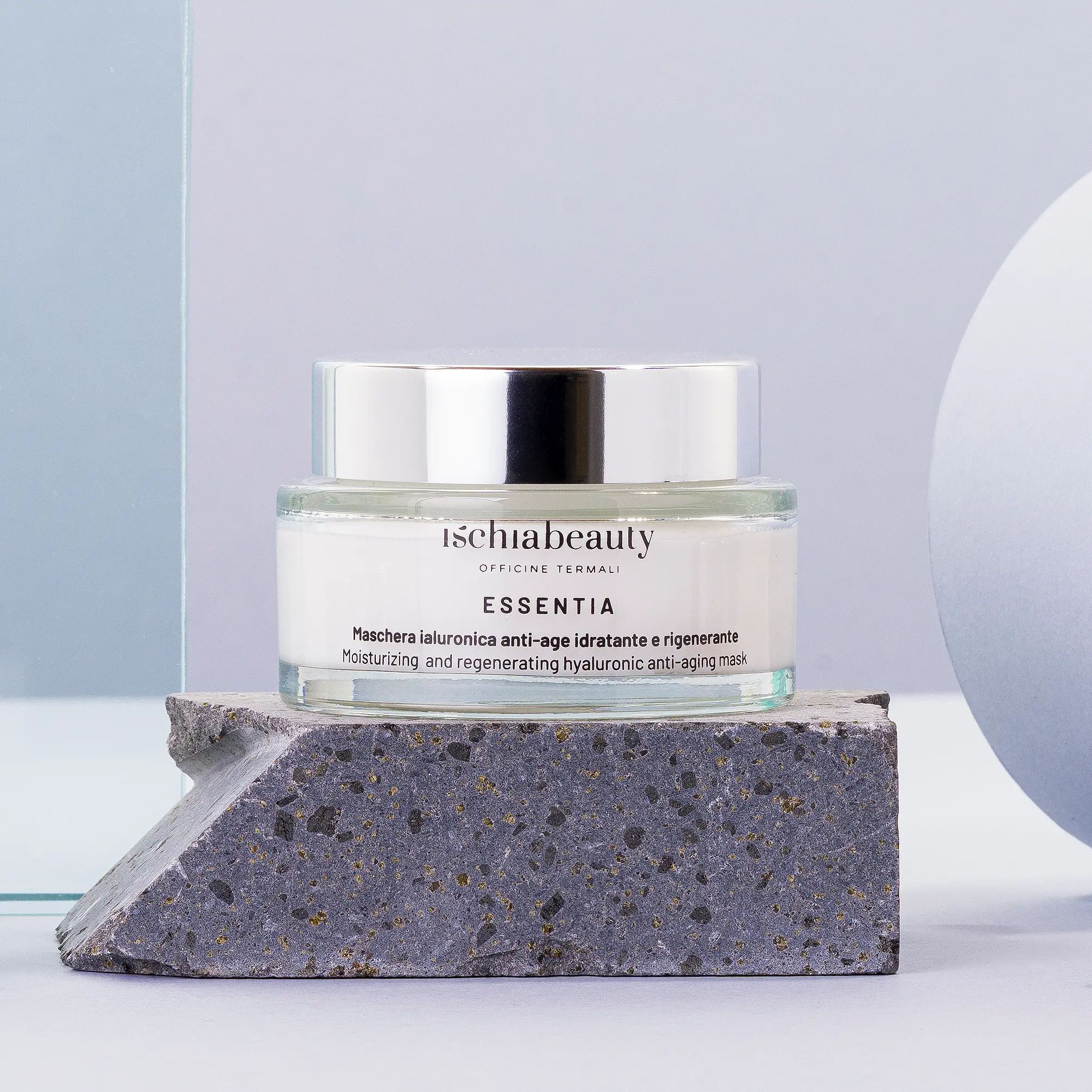 Vaso in vetro, coperchio argentato. Scritta: ischiabeauty ESSENTIA. Su pietra.