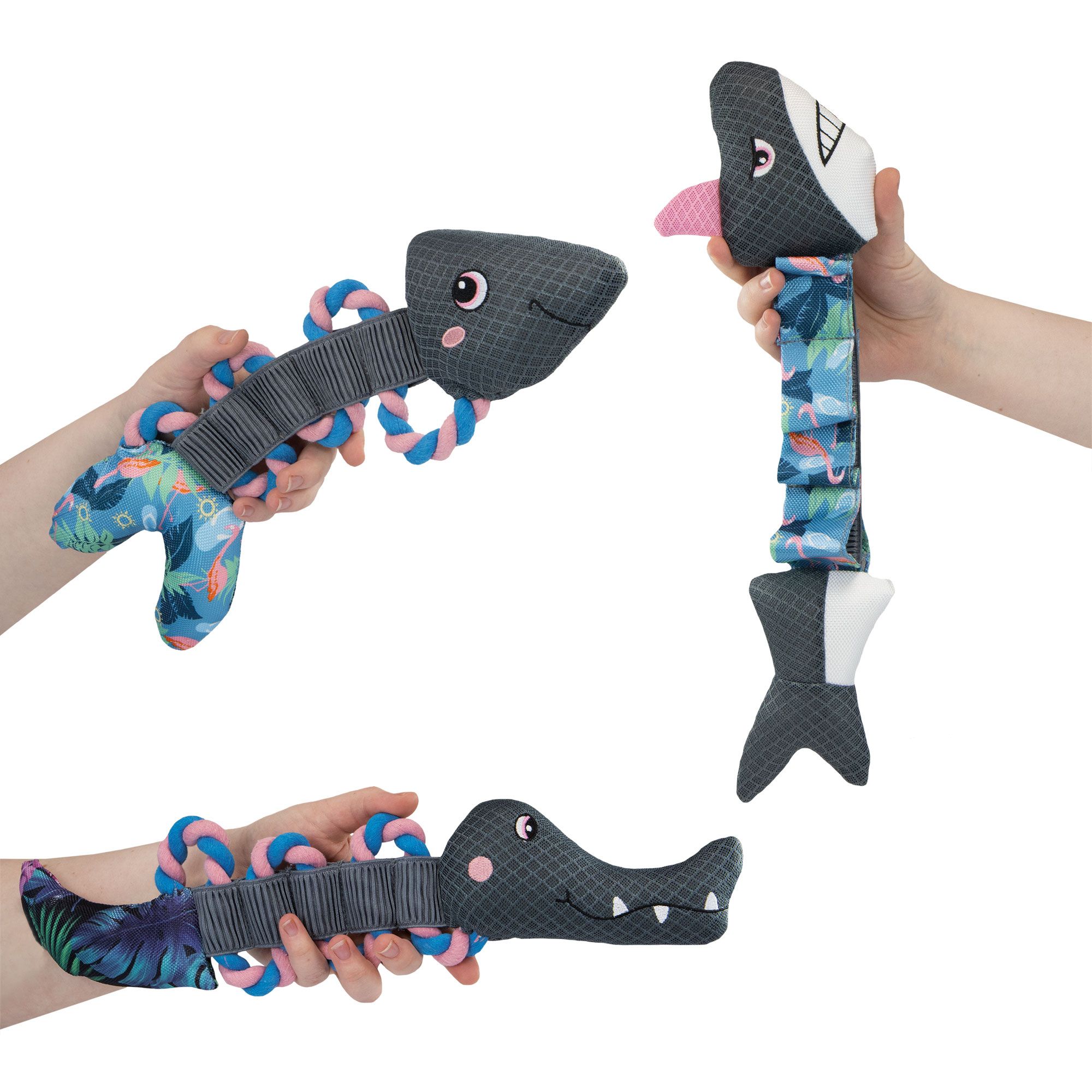 Tre giocattoli in mano a un cane. Un giocattolo a forma di pesce, un giocattolo con un design a coccodrillo e un giocattolo con un design a pesce.