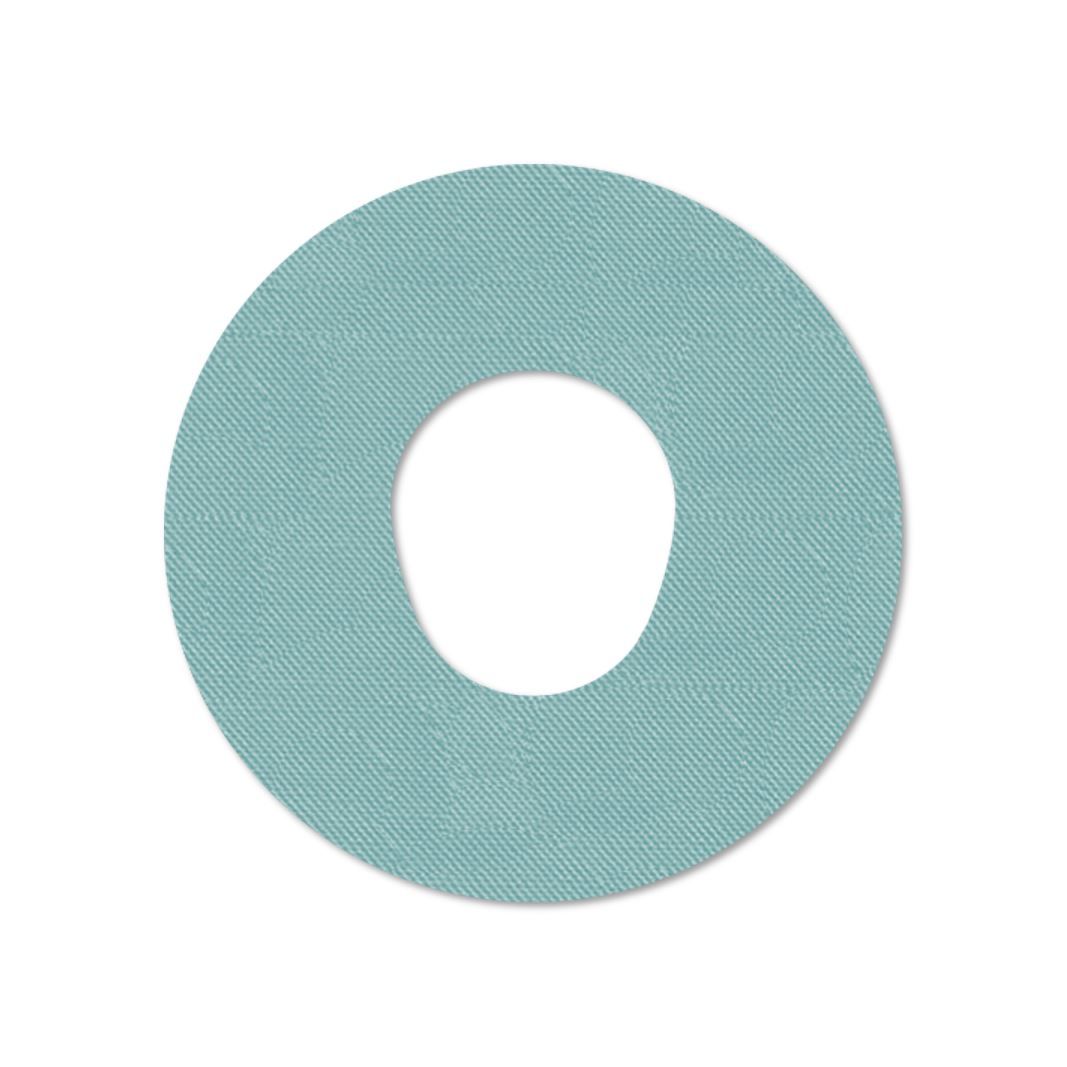 Cerotto di fissaggio rotondo azzurro con foro centrale. Tessuto.