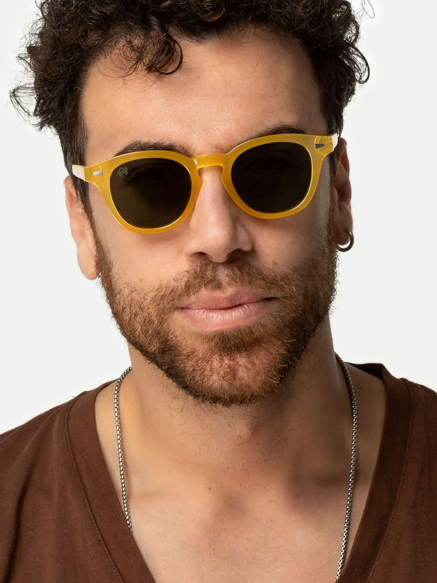 Uomo con occhiali da sole gialli con lenti rotonde. Primo piano. Camicia marrone.
