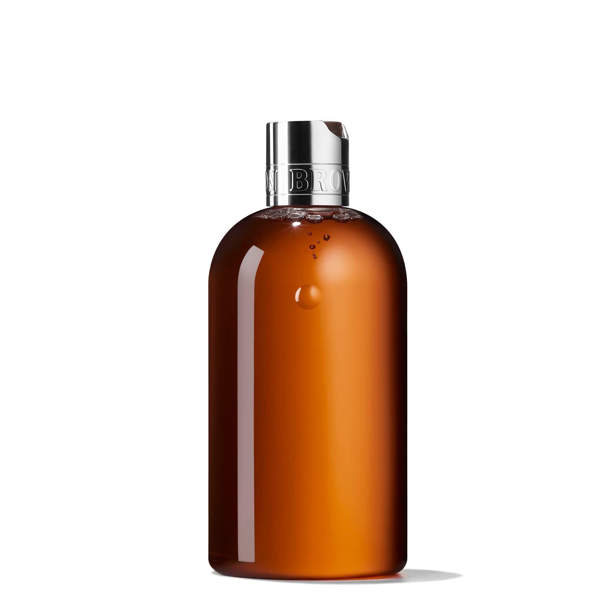 Flacone marrone con tappo argentato. Scritta: Molton Brown. Liquido visibile. Su sfondo bianco.