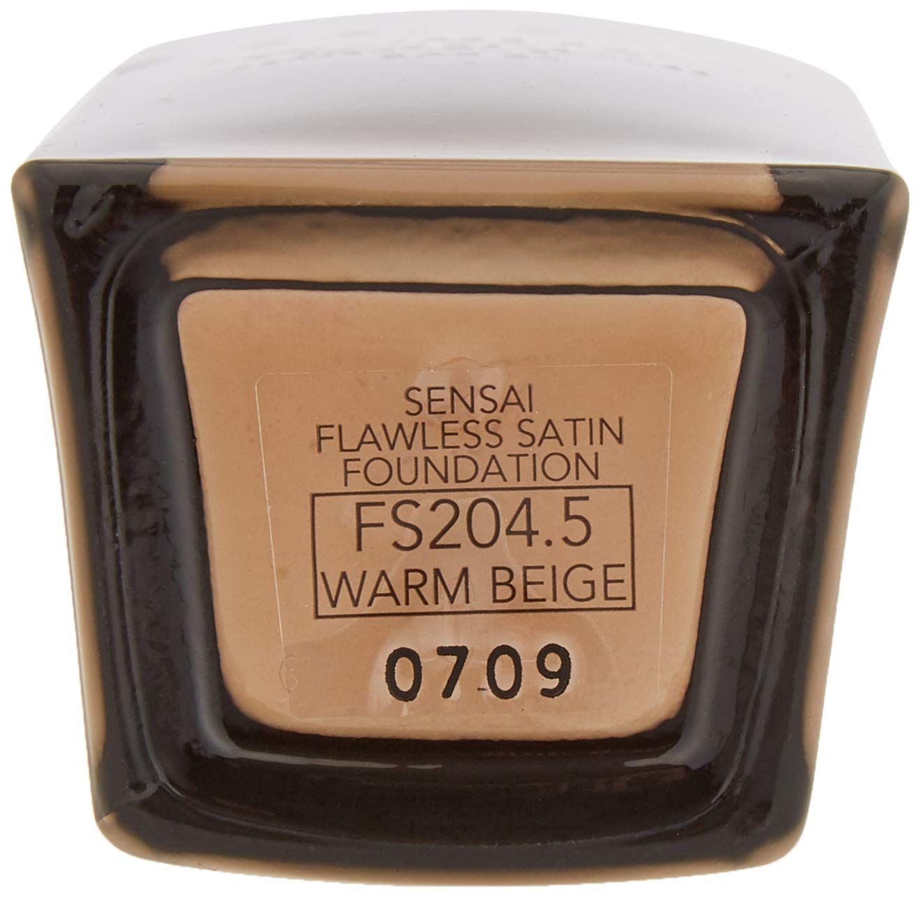 Fondo di un flacone con prodotto ed etichetta. Scritto: Sensai, Flawless Satin Foundation, FS204.5, Warm Beige, 07.09.