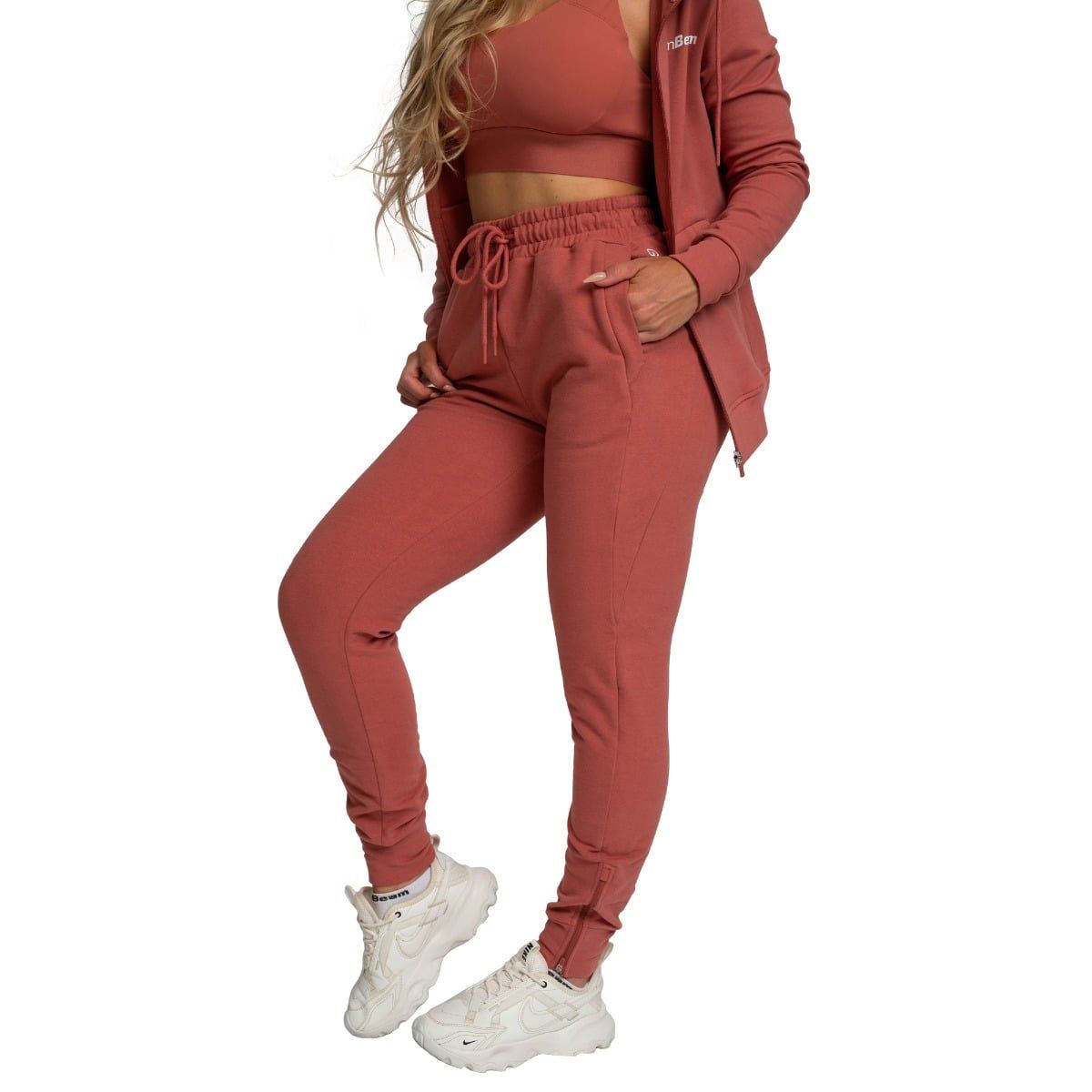 Pantaloni da jogging da donna color cannella, taglio slim, con coulisse e tasche, abbinati a bralette e felpa con cappuccio.