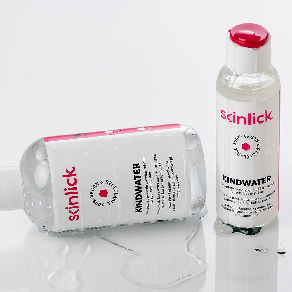 Due flaconi di SKINLICK Kindwater acqua micellare, uno sdraiato. Liquido trasparente.