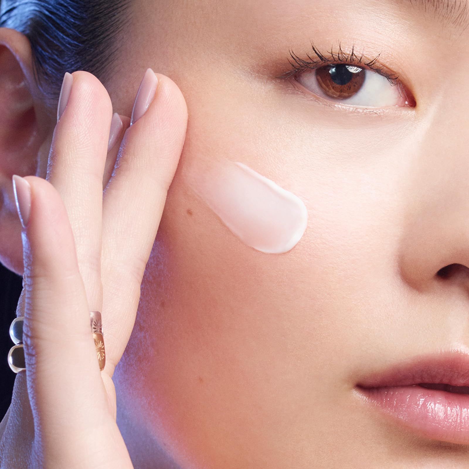 Primo piano di una donna che applica la crema sulla pelle. Prodotto visibile.