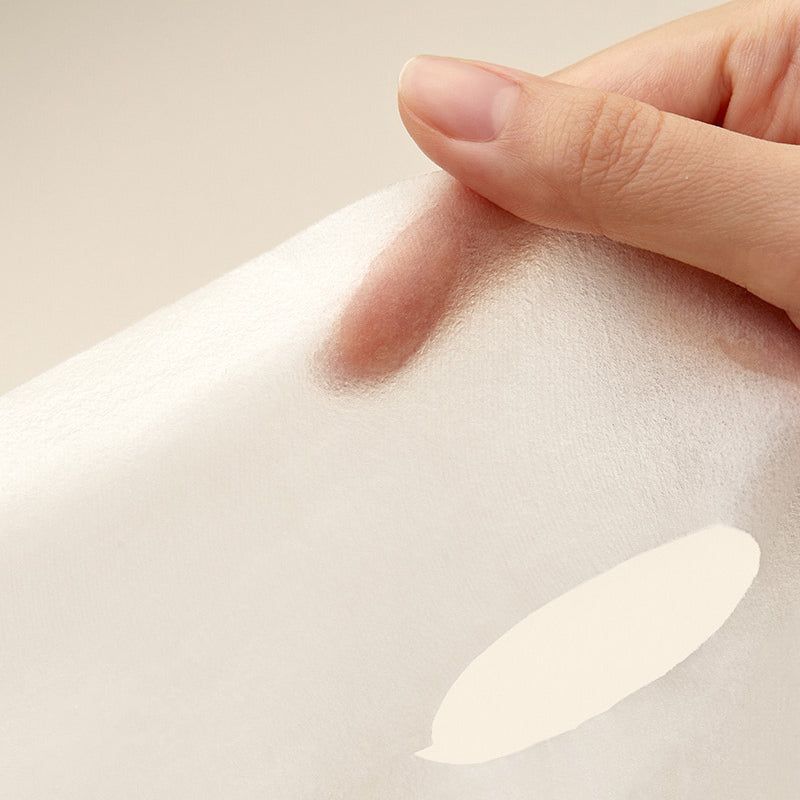 Mano che tiene un tessuto bianco trasparente. Visibile una macchia ovale color crema.