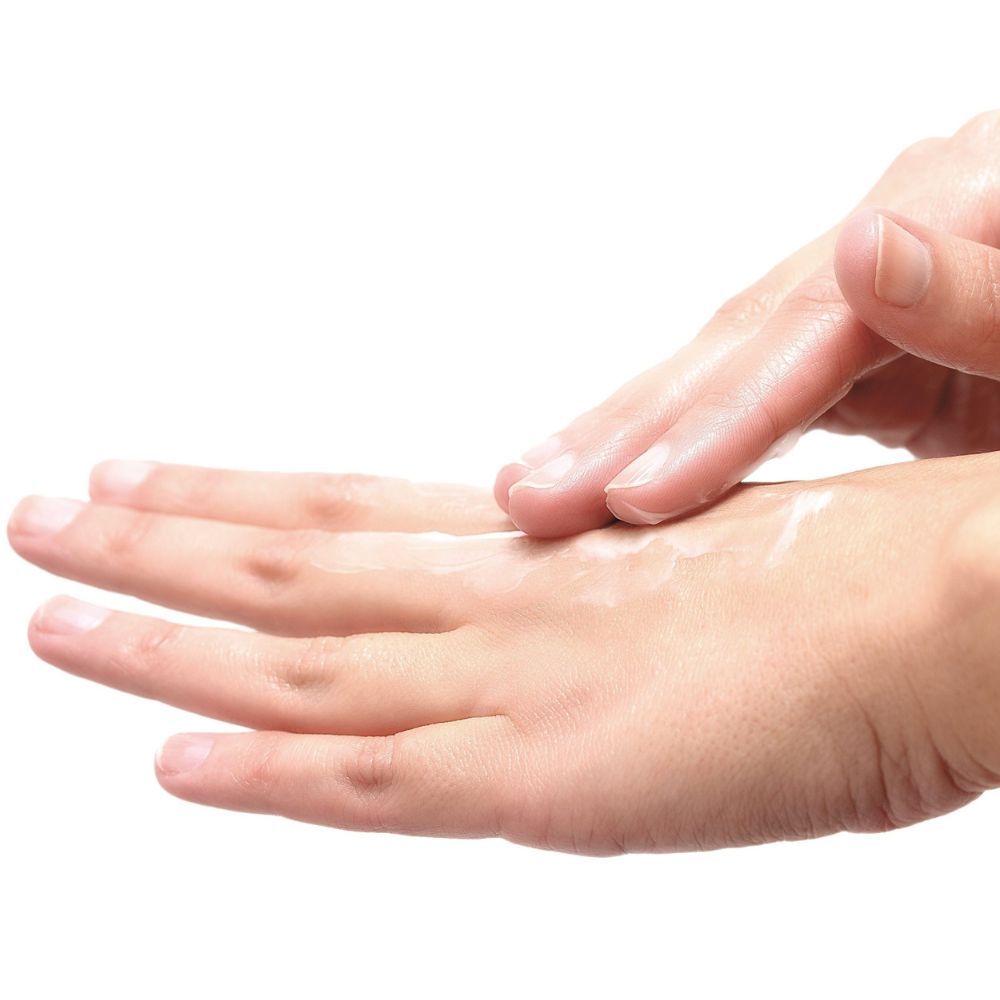 Primo piano di una mano che applica la crema sull'altra mano. La pelle è visibile.