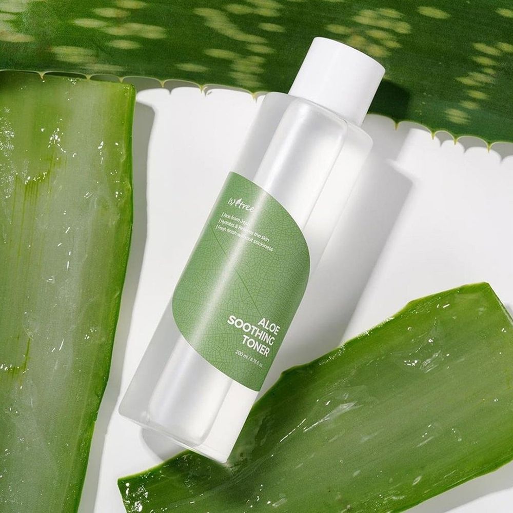 Flacone trasparente con tappo bianco. Etichetta verde con testo: Aloe Soothing Toner. Foglie di aloe vera.