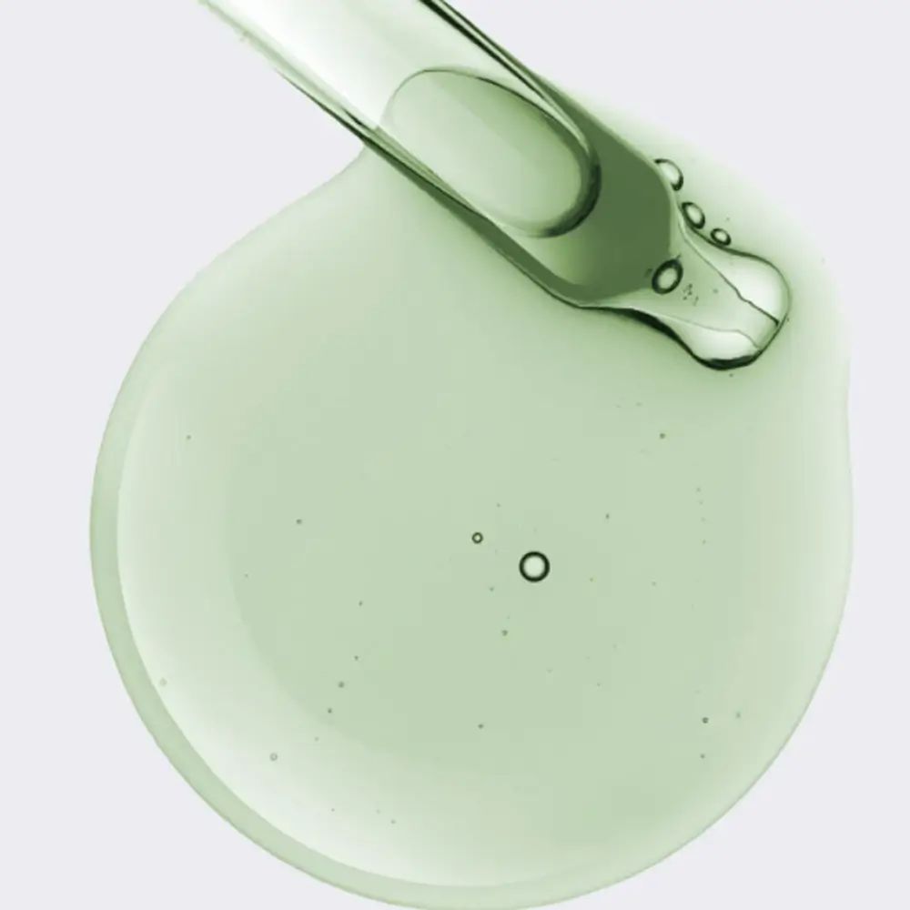 Siero verde traslucido con pipetta. Il liquido forma una goccia rotonda con piccole bolle.
