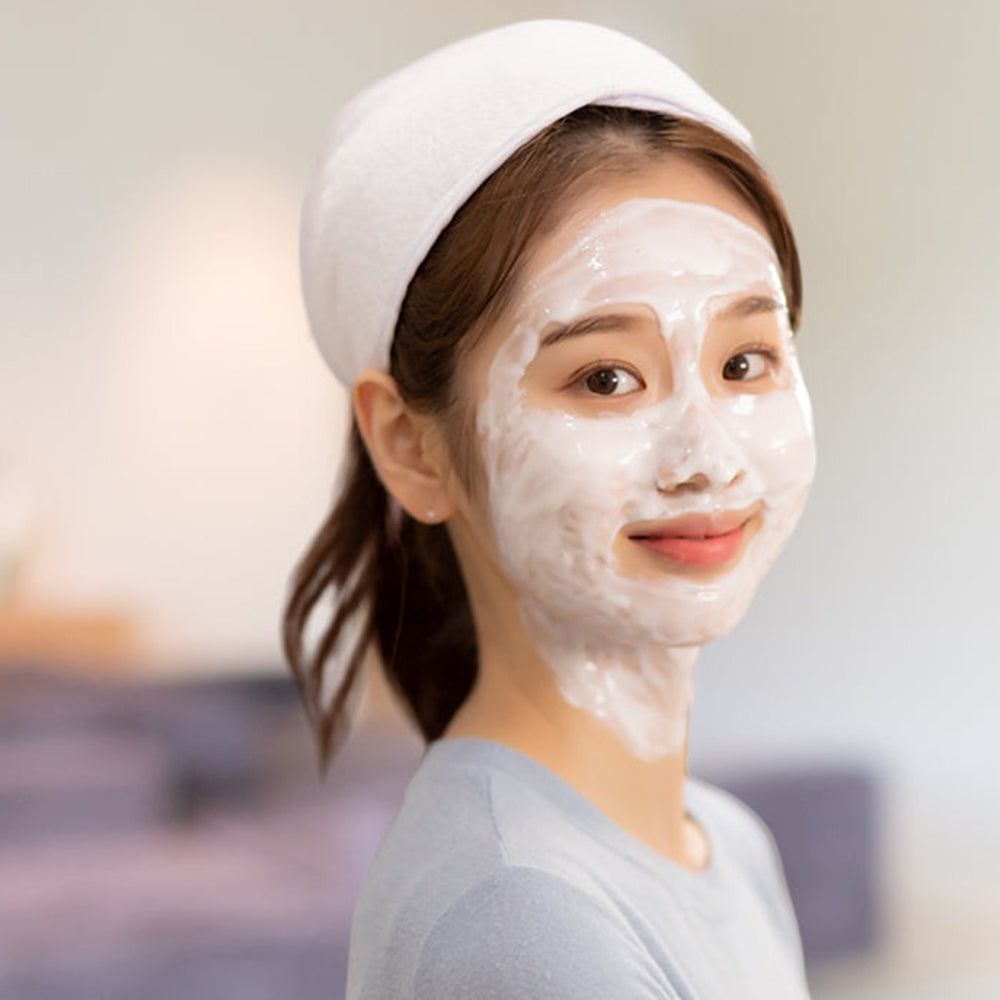 Donna con maschera viso bianca e fascia. Sorride alla fotocamera.