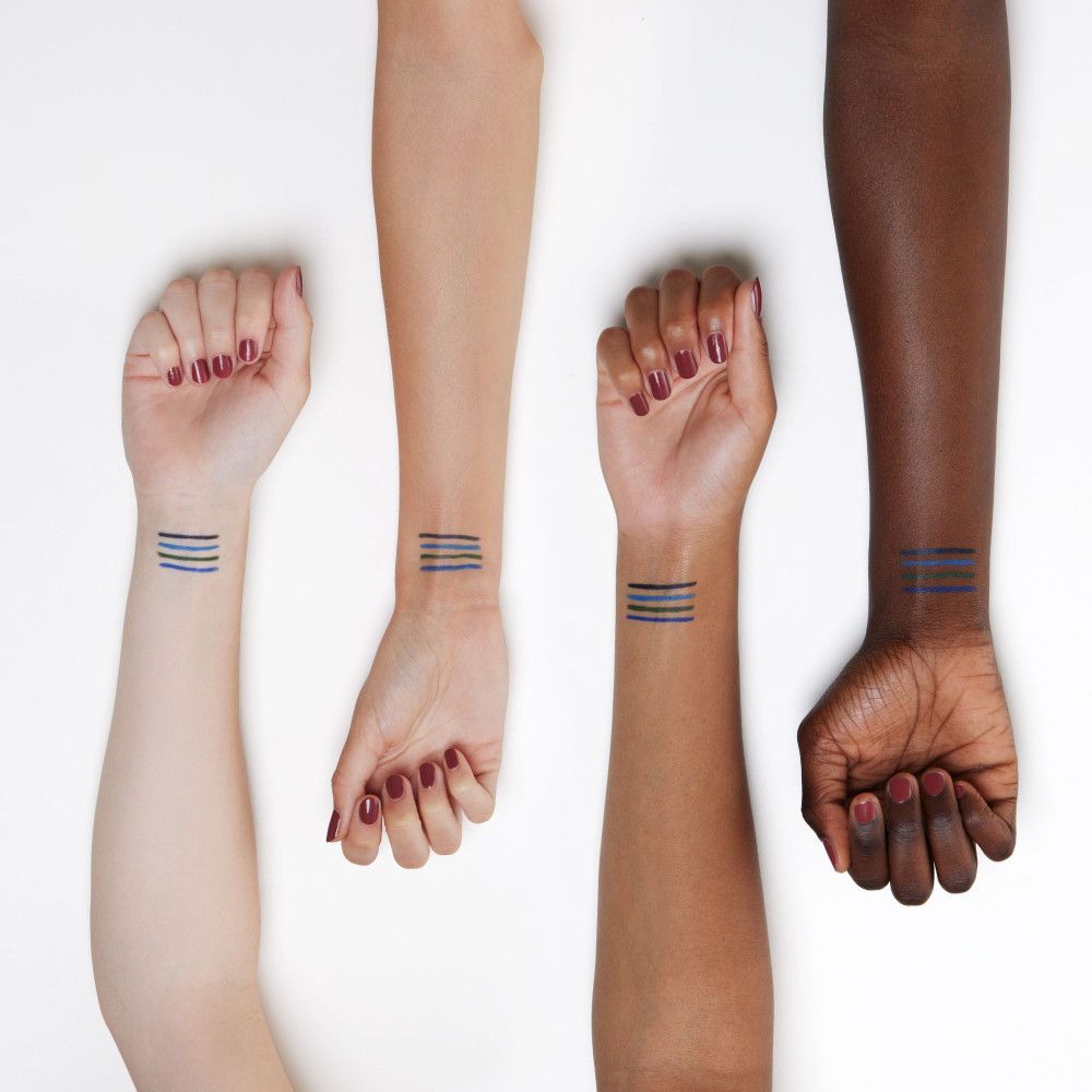 Quattro braccia con diverse tonalità di pelle. Tratti di kajal blu applicati sui polsi.