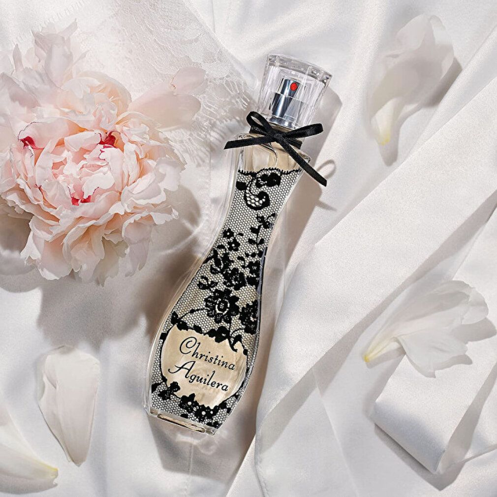 Flacone di Eau de Parfum Christina Aguilera su tessuto bianco con peonia.