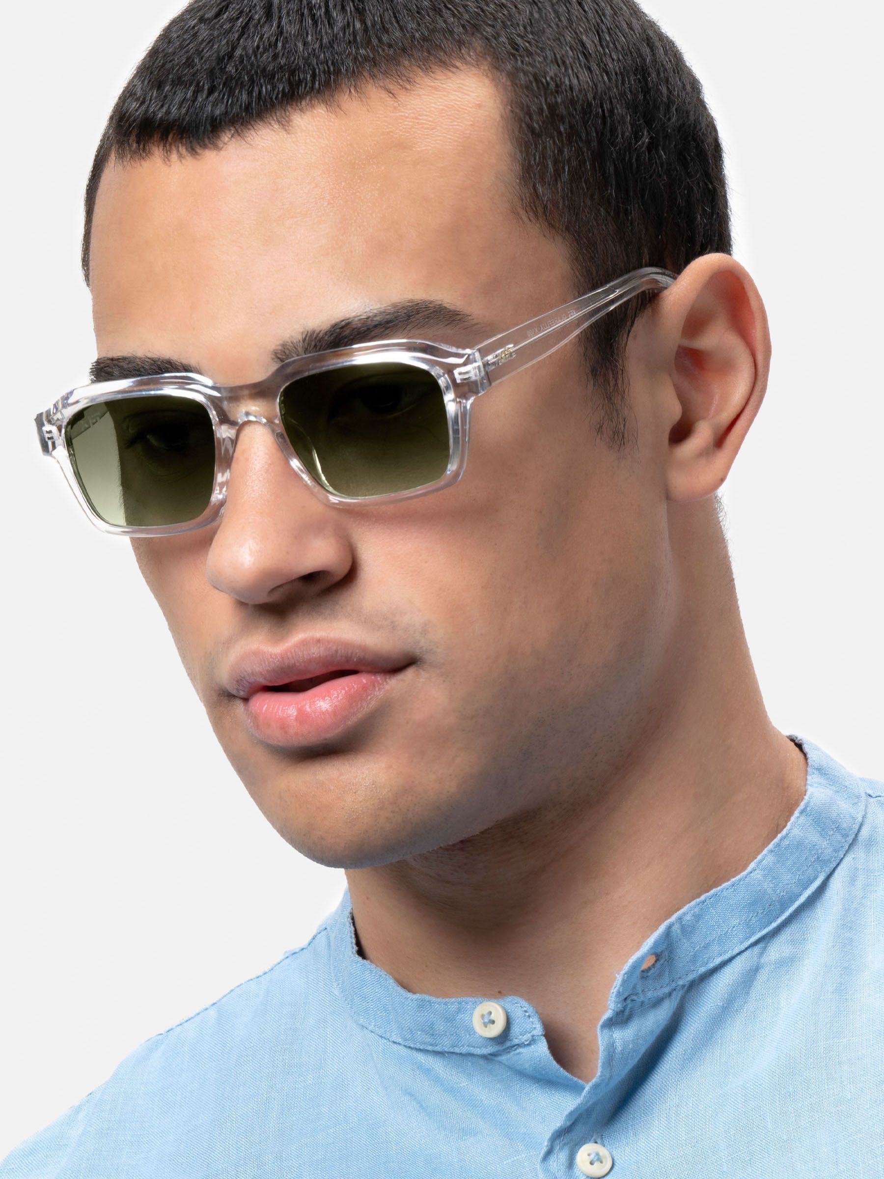 Uomo con occhiali da sole trasparenti con lenti verdi. Primo piano, forma rettangolare. Logo XFT sulla lente.