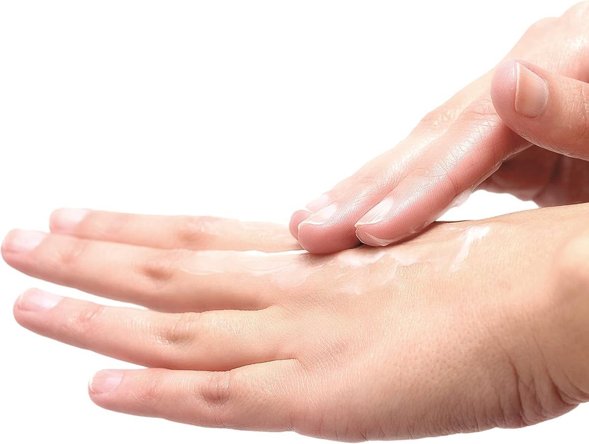 Mani, una mano applica la crema sull'altra. La crema è visibile.
