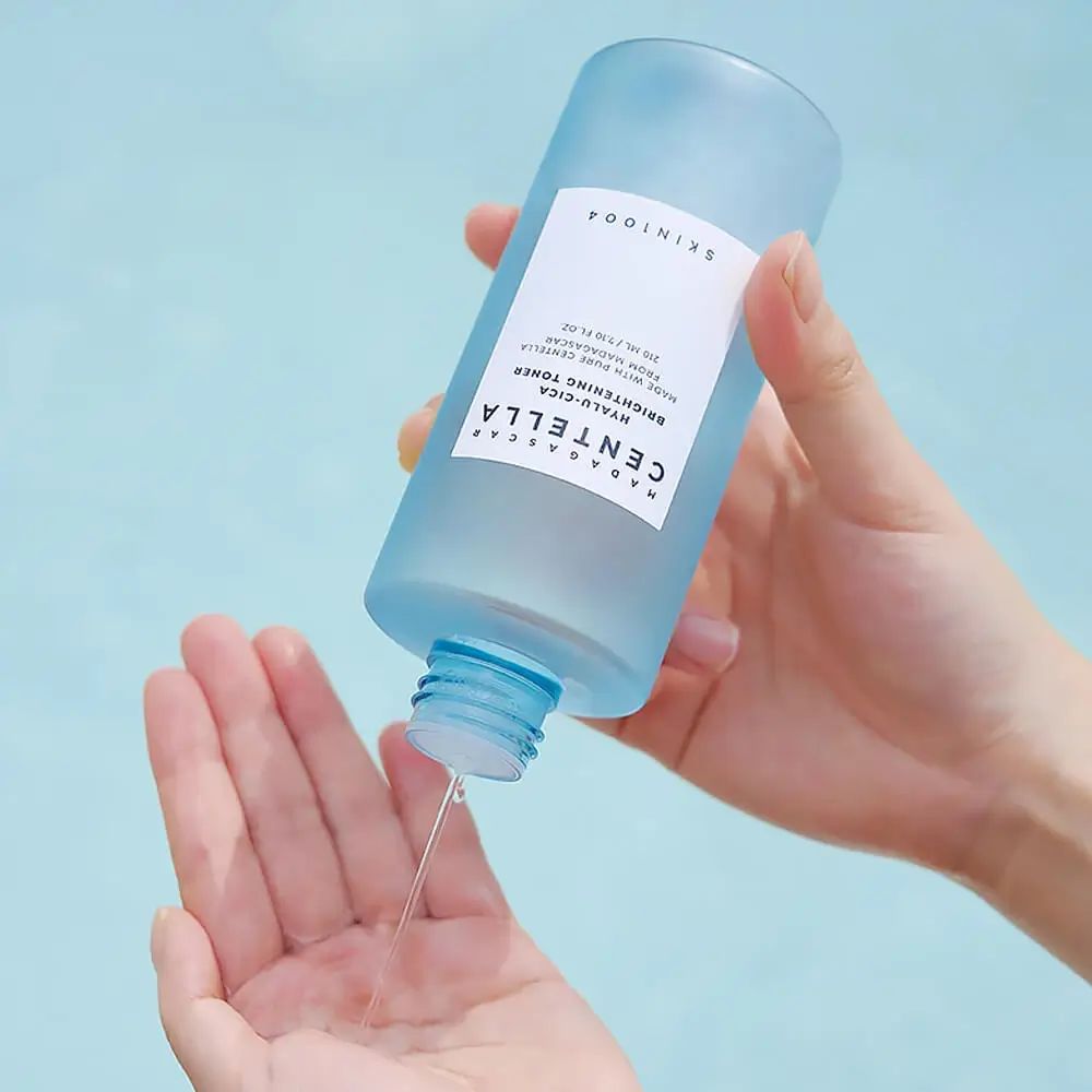 Flacone blu trasparente, liquido versato nella mano. Scritte: SKIN1004, MADAGASCAR CENTELLA, HYALU-CICA.