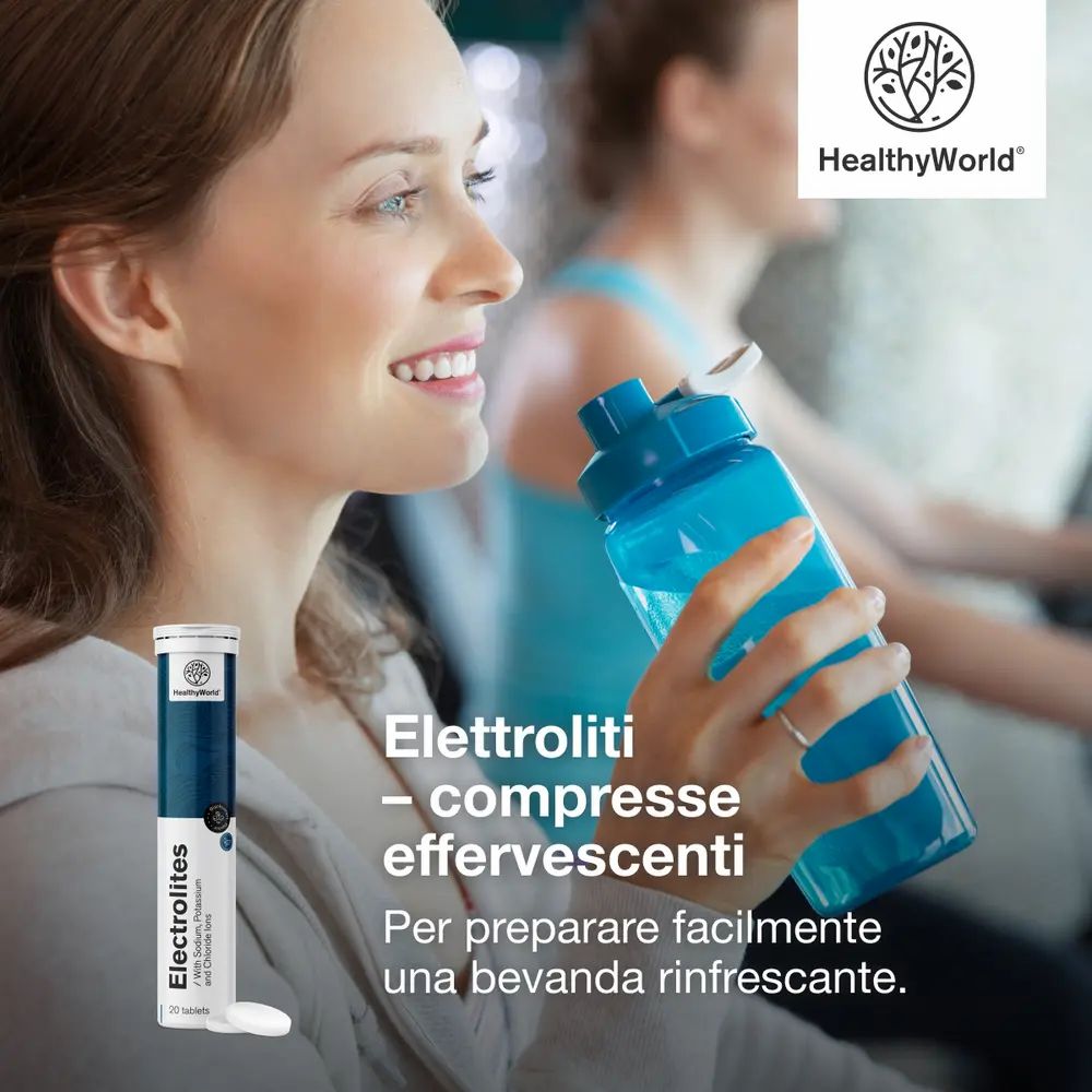 Donna beve da una borraccia blu dopo lo sport, accanto un tubo di compresse effervescenti di elettroliti.