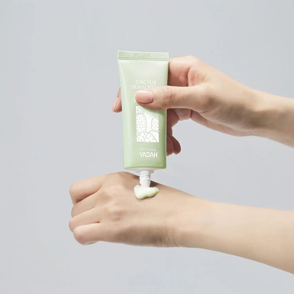 Tubo verde con stampa. Prodotto applicato sulla mano. Scritta: Cactus Sunscreen, YADAH.