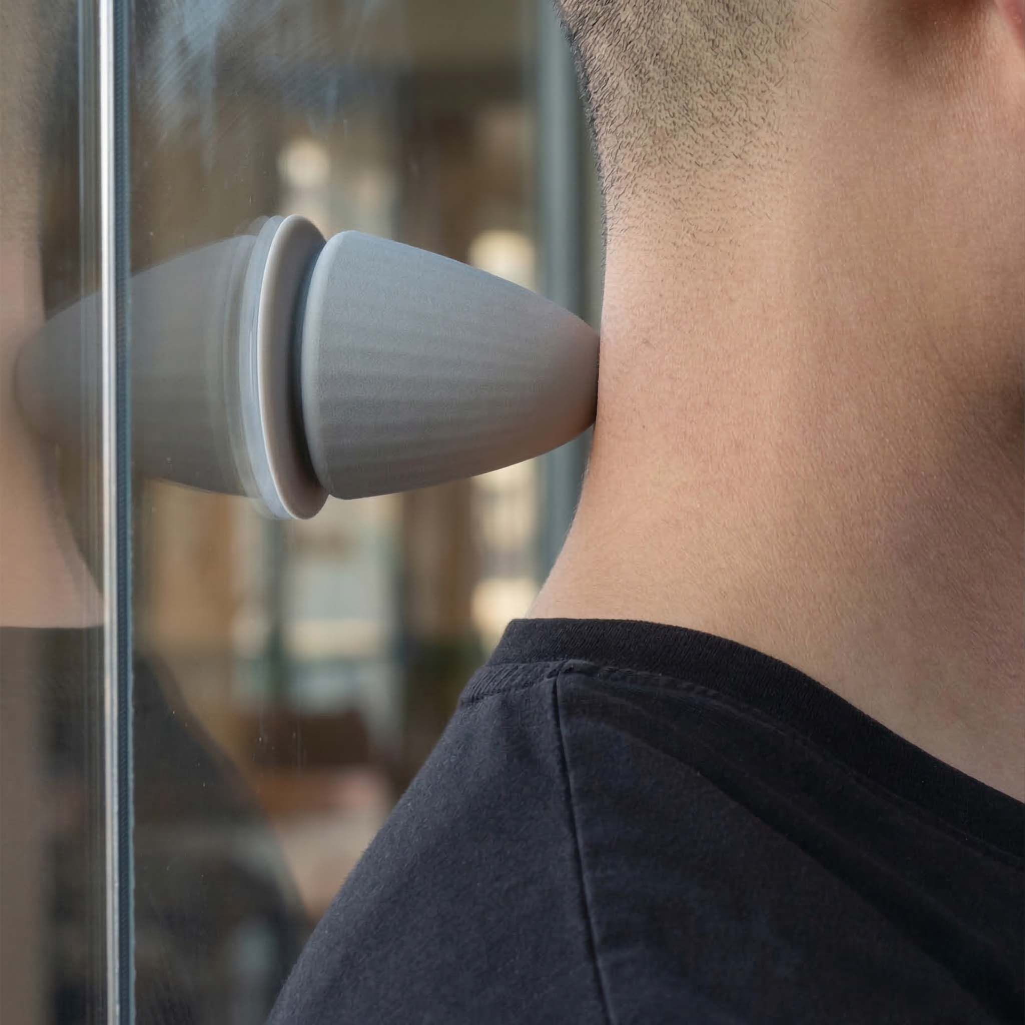 Prodotto grigio a forma di cono usato sul collo di una persona. Riflesso sul vetro.