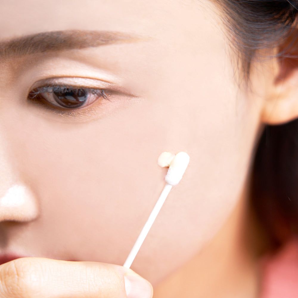 Primo piano di un viso. Un cotton fioc tocca la pelle. Tono della pelle.