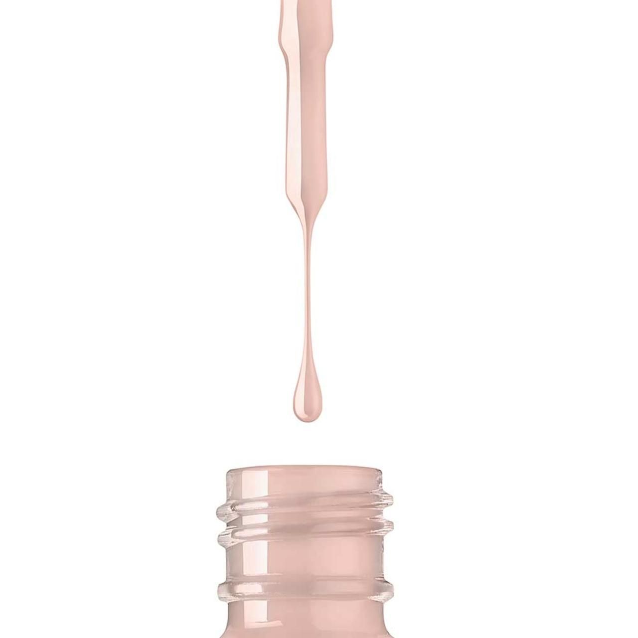 Primo piano di un flacone di smalto per unghie. Goccia di smalto beige che cade dal collo. Collo filettato.