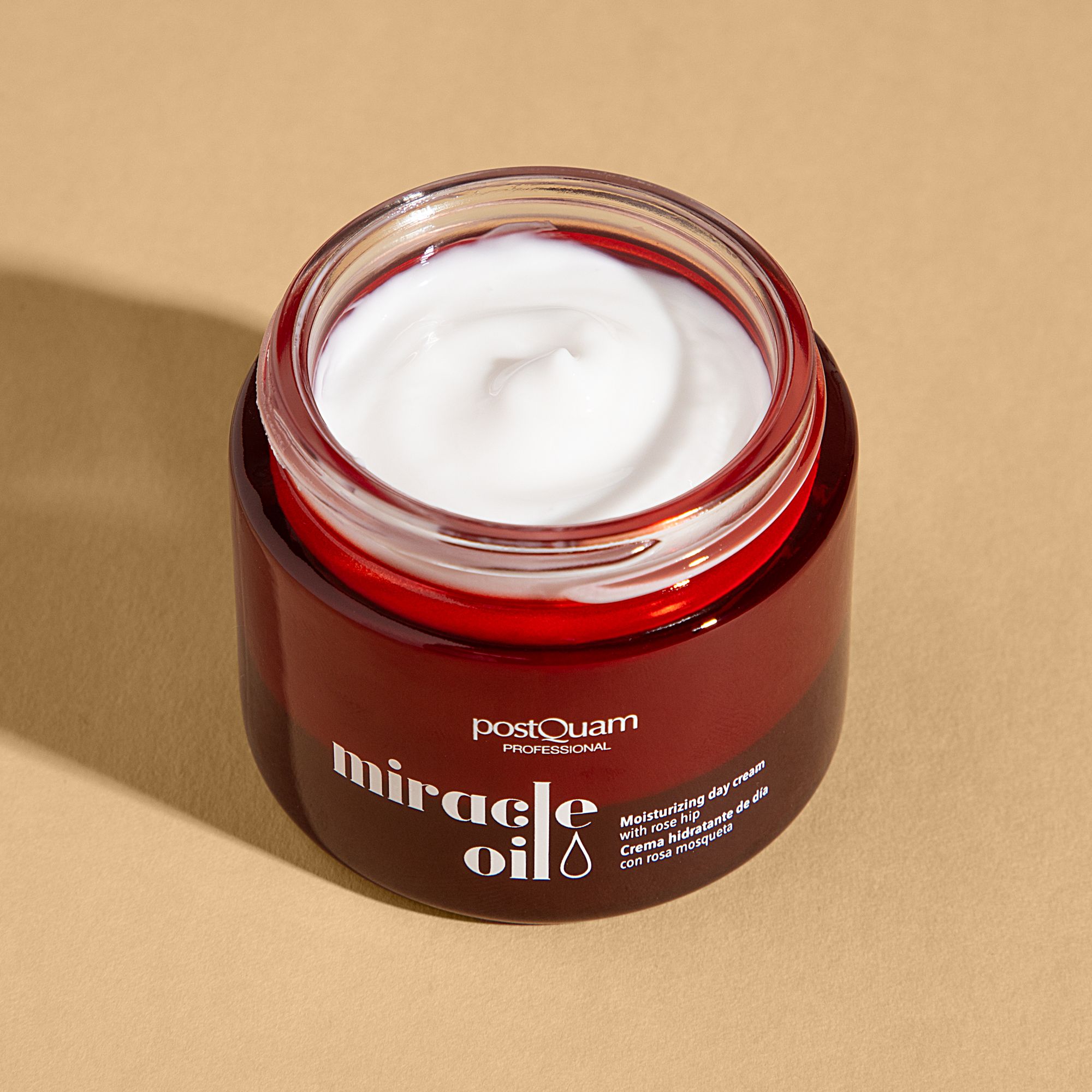 Vaso di crema marrone aperto con crema bianca. Scritta: Postquam Professional, Miracle Oil. Testo: Moisturizing day cream with rose hip.