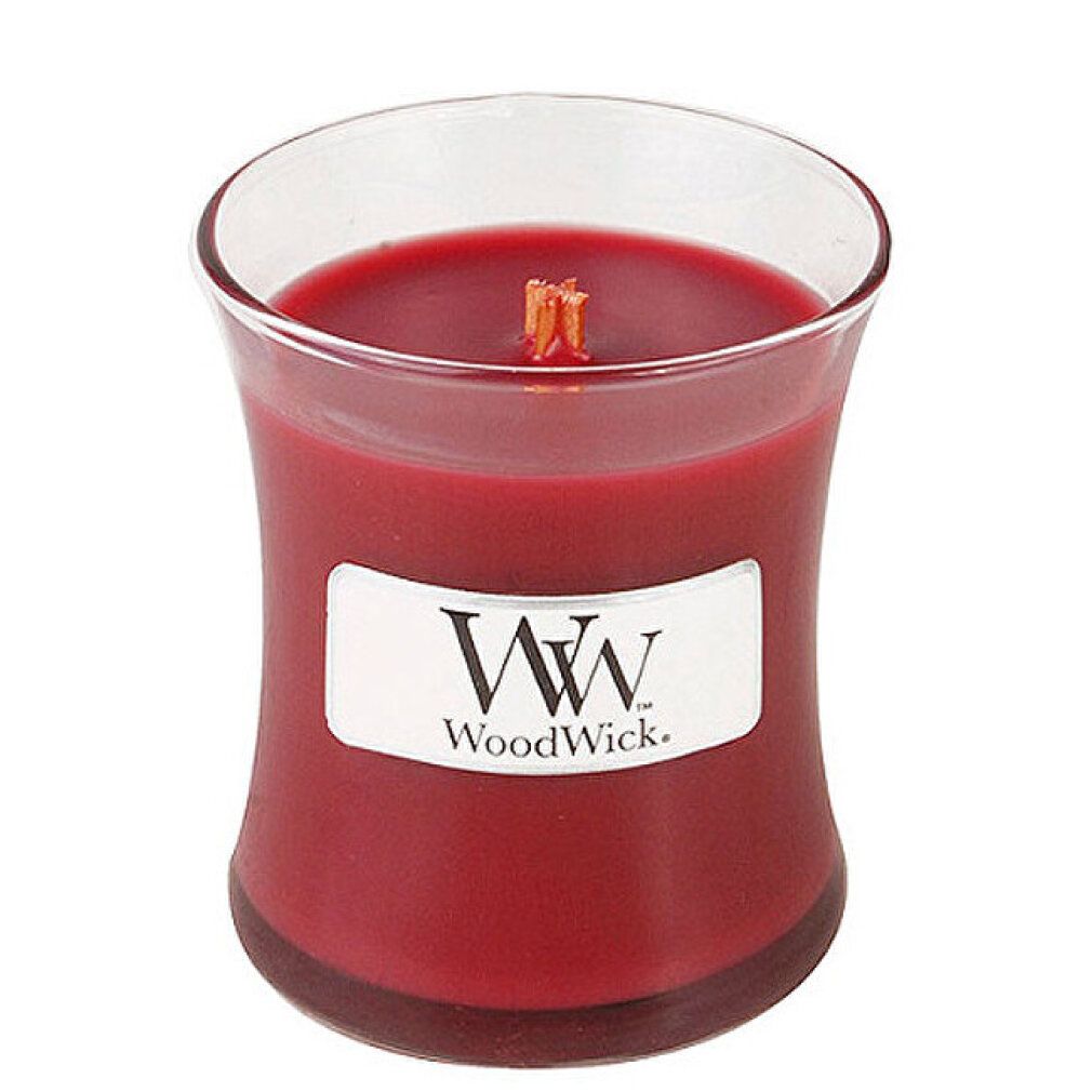 Candela di vetro con cera rossa. Etichetta rettangolare con logo e testo. Scritta: WoodWick. Stoppino in legno.