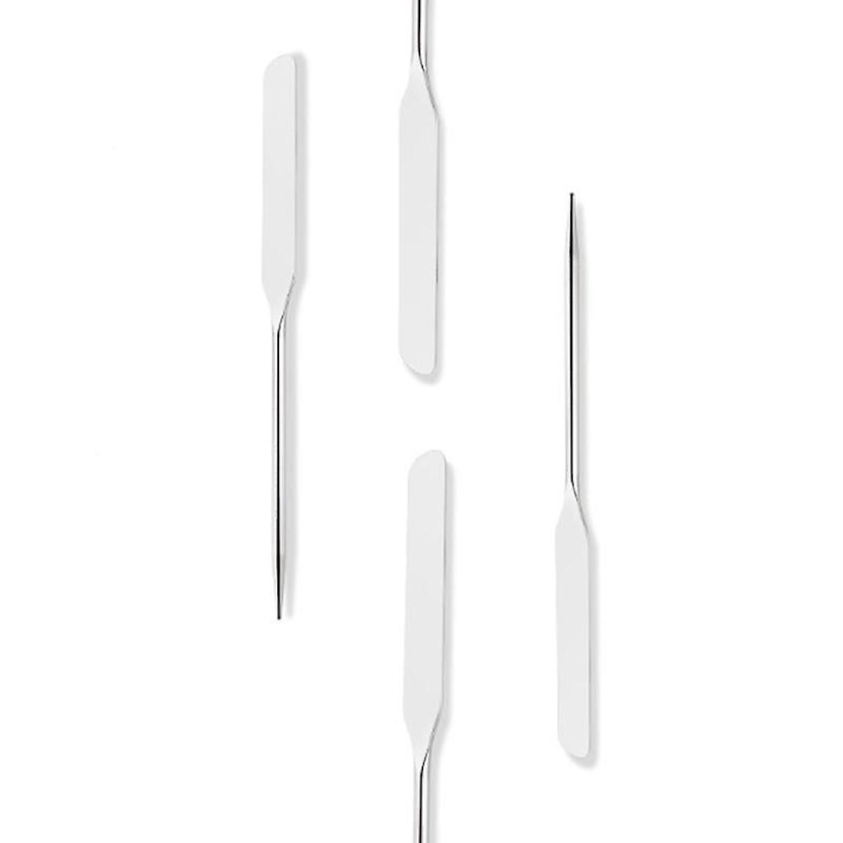 Quattro spatole per trucco di varie dimensioni e forme su sfondo bianco.
