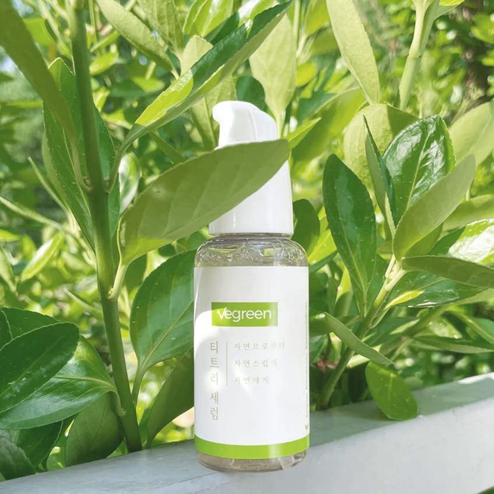 Siero trasparente in flacone bianco con dosatore, davanti a foglie verdi. Scritta: Vegreen, caratteri coreani.