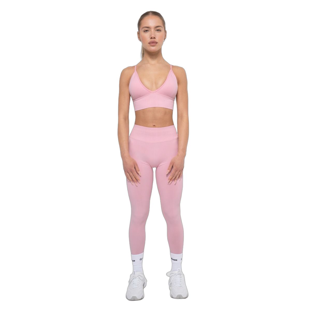 Donna con completo sportivo senza cuciture rosa baby: leggings a vita alta e reggiseno coordinato.