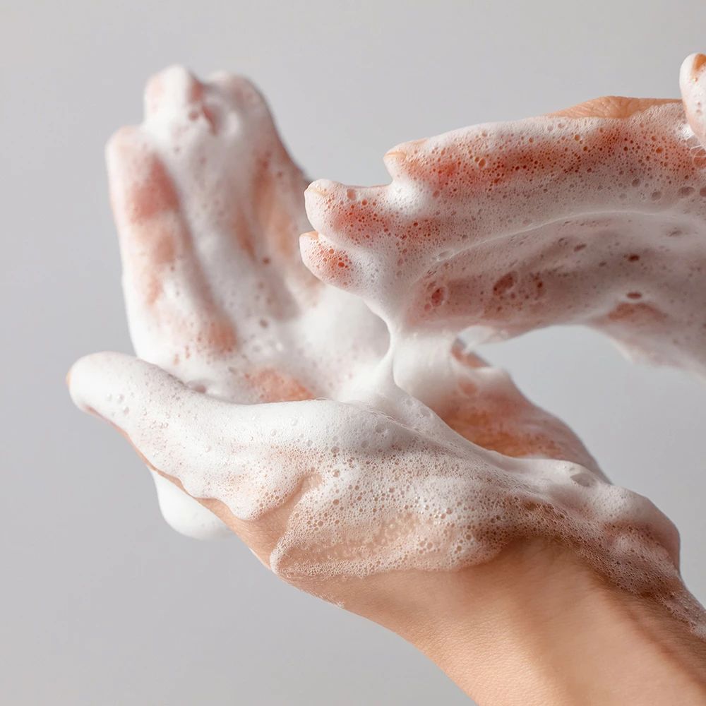 Mani coperte di schiuma bianca. La schiuma copre palmi e dita. Colore della pelle chiaro.