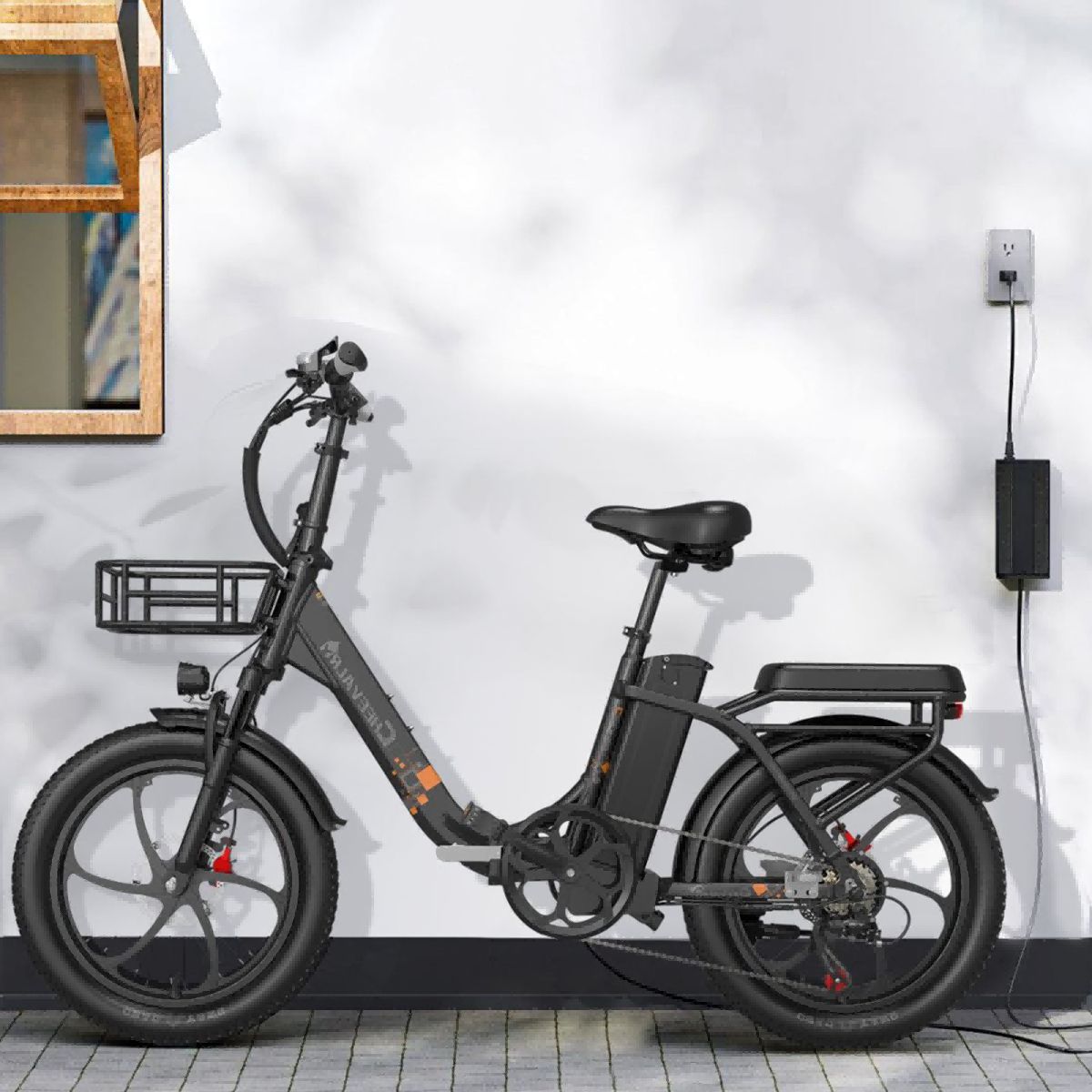 Bicicletta elettrica nera con cestino, contro un muro con presa e caricatore. Sella e manubrio visibili.