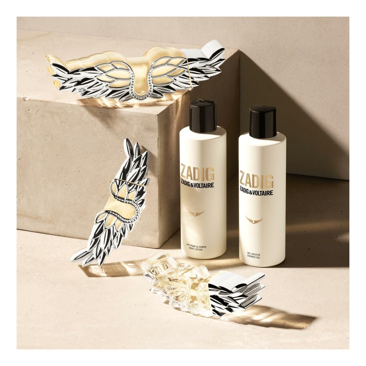 Due flaconi di gel doccia Zadig & Voltaire, decorazioni ad ali d'angelo. Su sfondo chiaro, ripresa in studio.