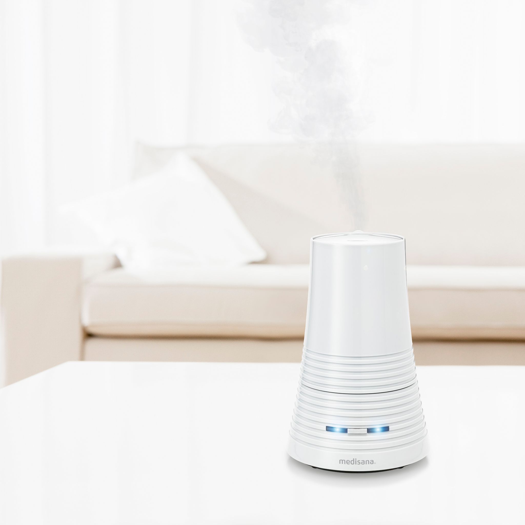 Umidificatore medisana AH 662 bianco su un tavolo, con uscita di vapore, in un soggiorno.