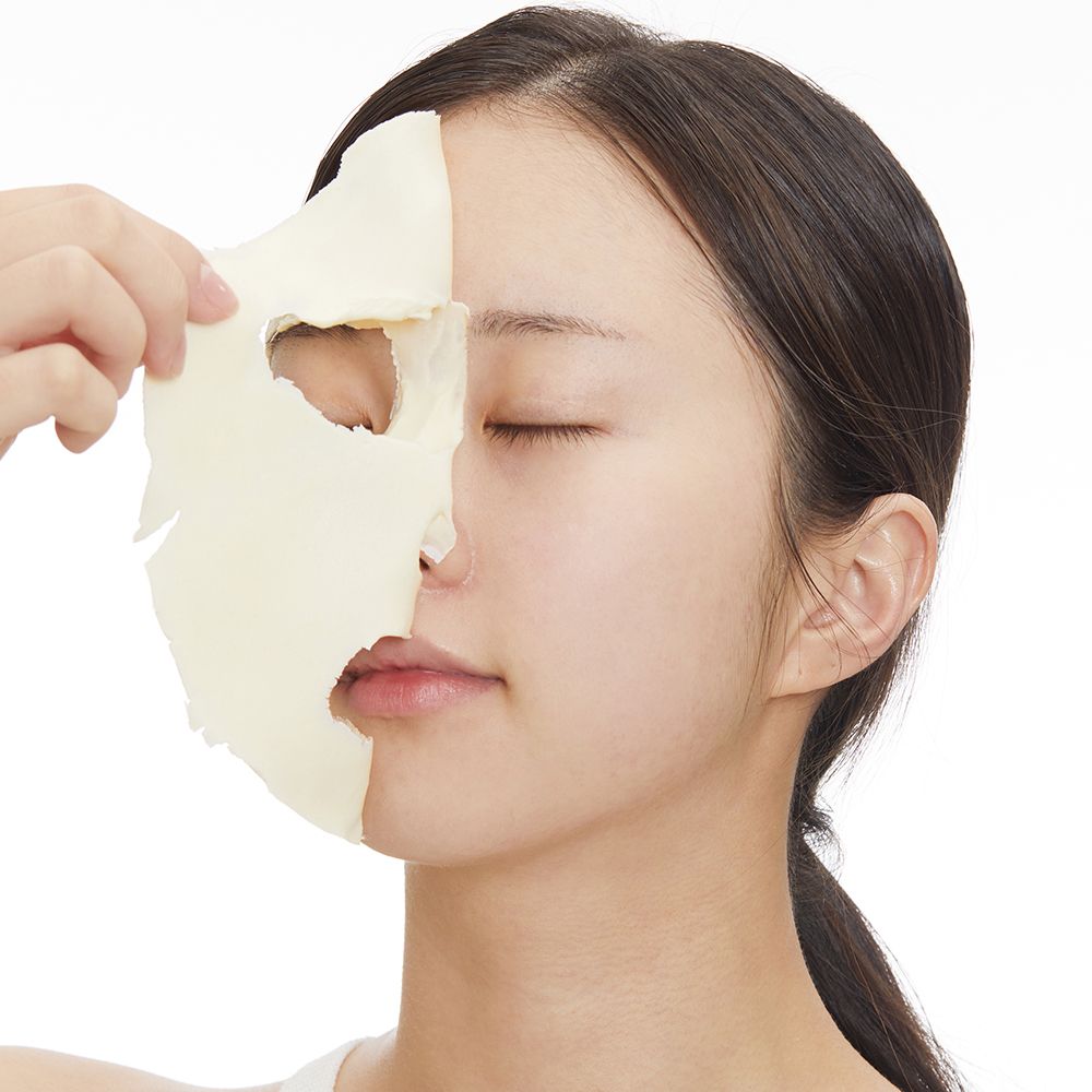 Una donna applica una maschera facciale che copre metà del suo viso.