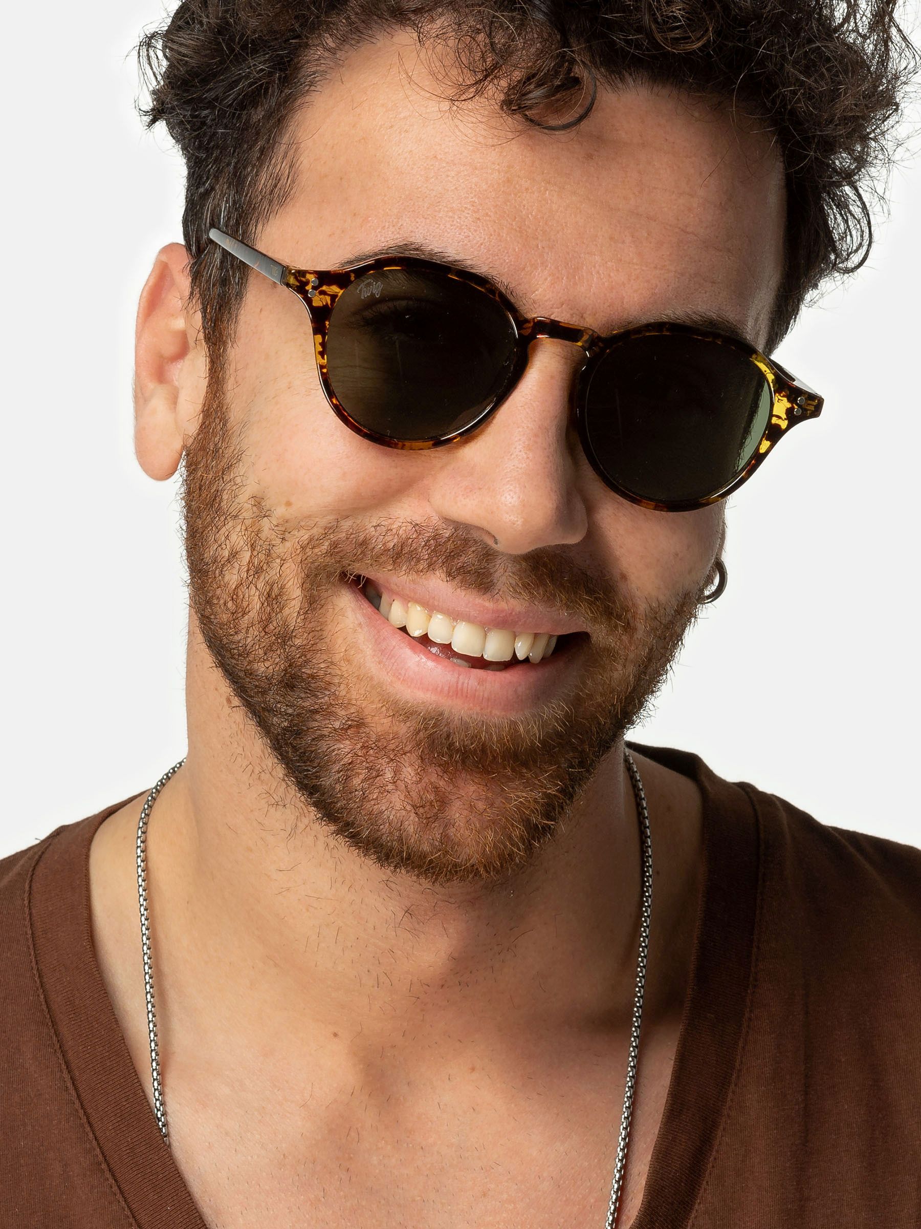 Uomo con occhiali da sole. Occhiali rotondi, motivo tartarugato marrone, lenti verdi. Primo piano.