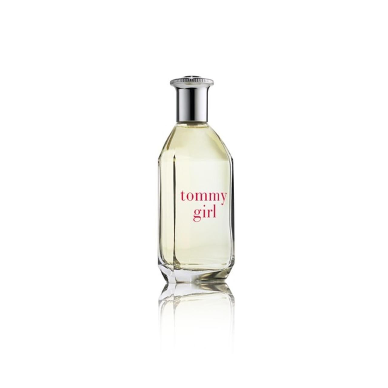 Flacone di profumo con tappo argentato e scritta rossa "tommy girl". Flacone trasparente, rettangolare, con superficie riflettente.