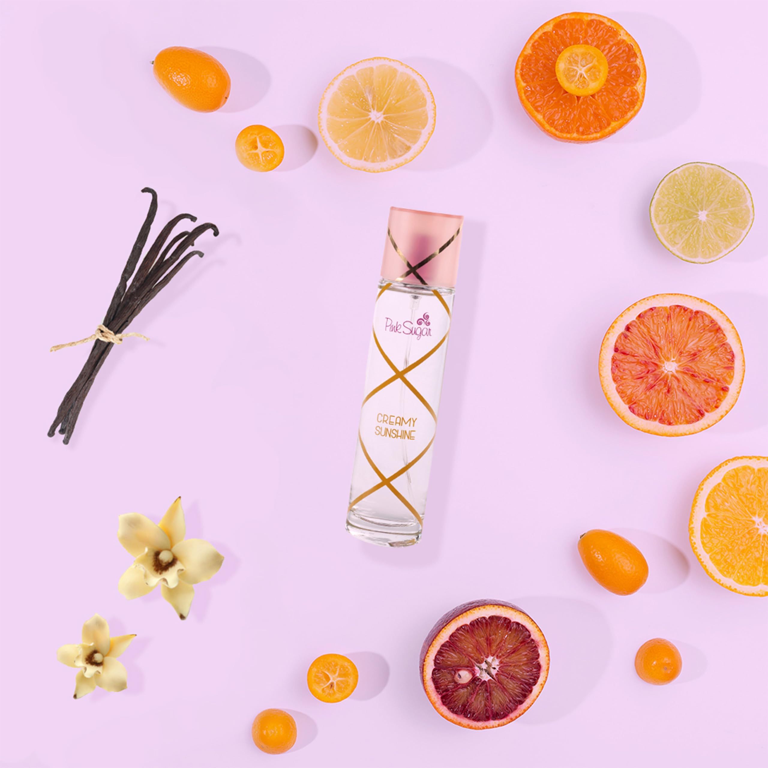 Flacone in vetro con tappo rosa, circondato da frutta e fiori. Logo Pink Sugar visibile.