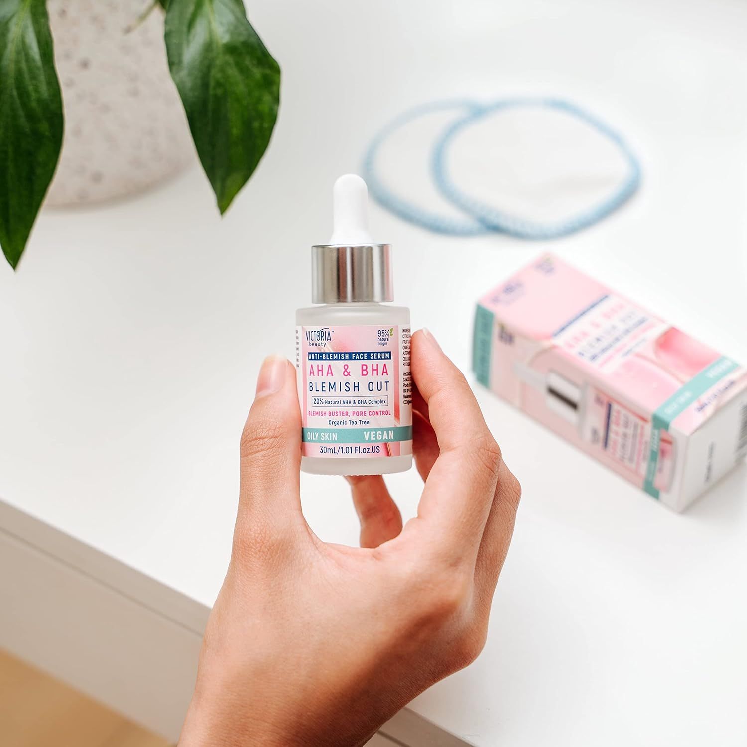 Flacone di siero con pipetta. Scritta: AHA & BHA Blemish Out. Tenuto in mano, accanto confezione e dischetti.