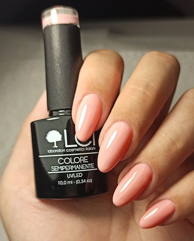 Flacone di smalto e unghie smaltate. Flacone nero. Unghie smaltate di rosa.